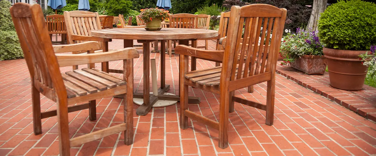 A brick patio with multiple wood tables and chairs