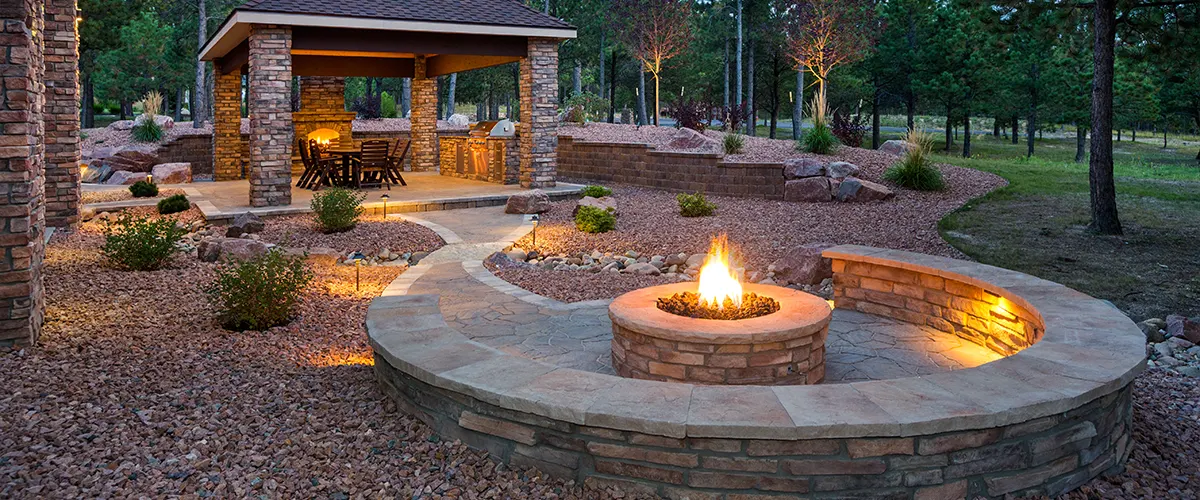 A beautiful outdoor space at night with a lit brick fireplace