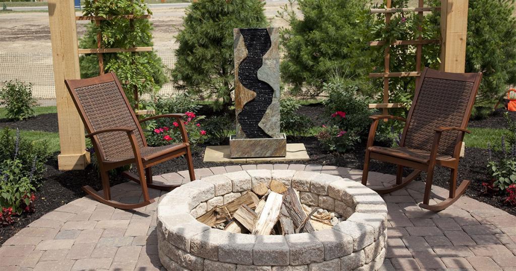 A brick fire pit with wood and two chairs