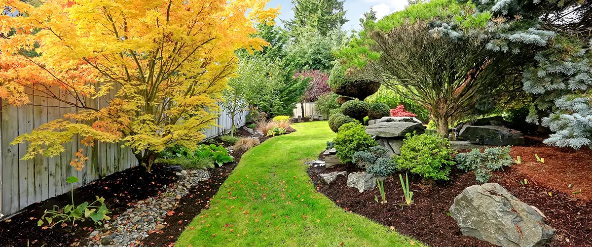 The cost of landscaping for a large backyard with a lawn, trees, and boulders