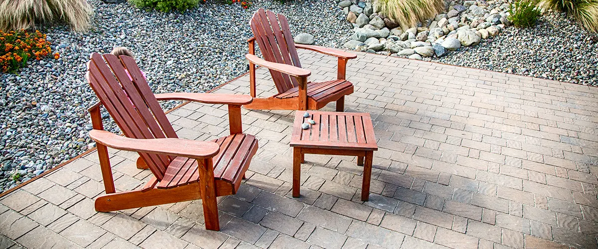 A paver patio with two wood chairs and a table