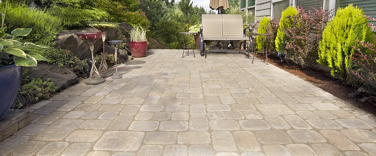 A concrete vs pavers patio in a small garden