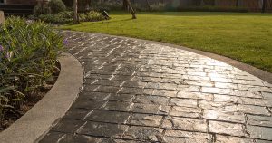 A stamped concrete walkway with a wet lawn