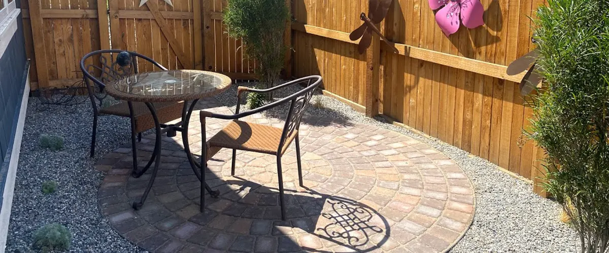 A backyard with a table and chairs on cobblestone