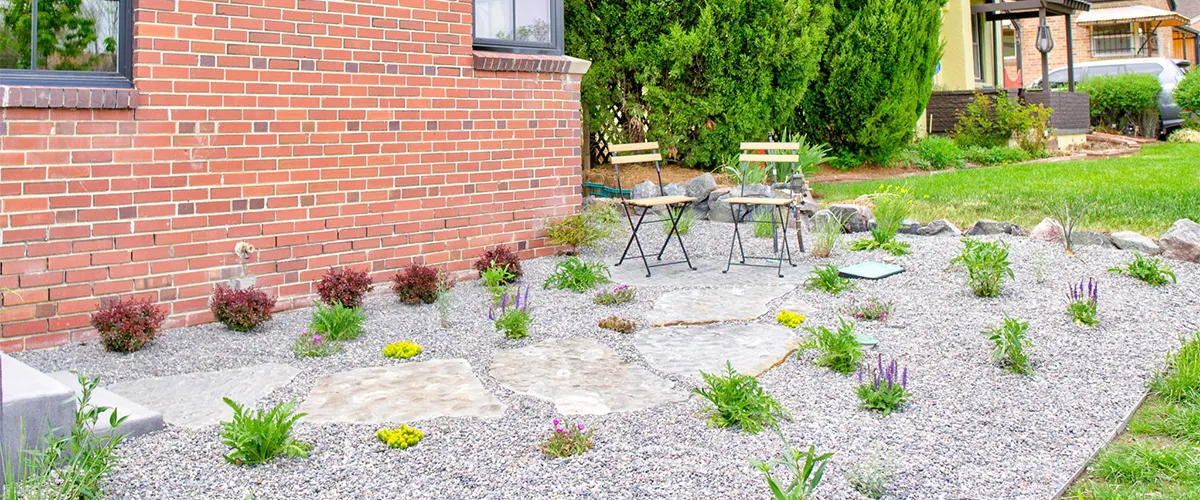 Flagstone material in a backyard surrounded by plants and gravel