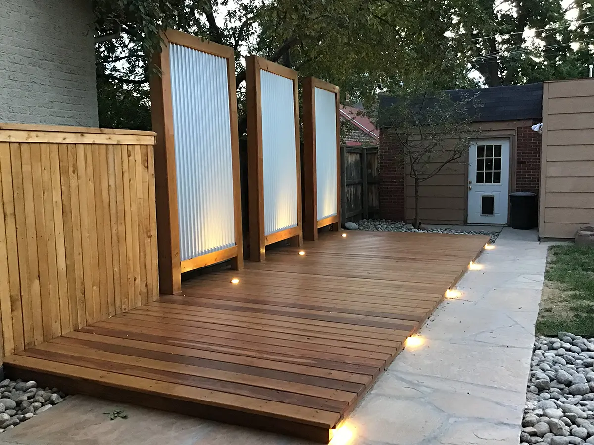 New wooden deck in a small backyard with light panels and paver patios