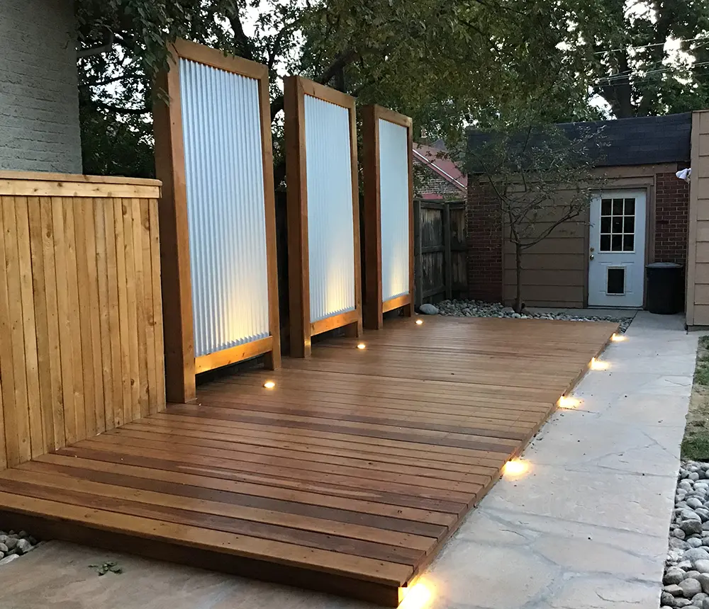 Custom deck build with built-in lighting and privacy screens in a small backyard