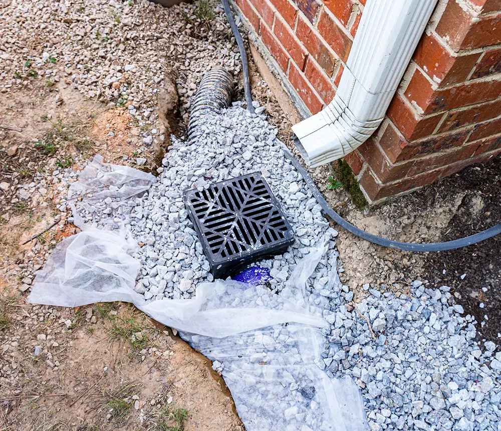 Closeup of a home downspout going into a french drain system