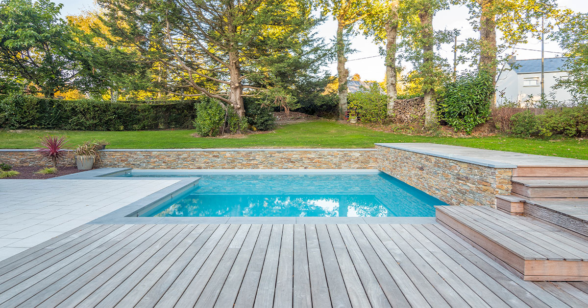 Pool deck with composite decking and retaining wall