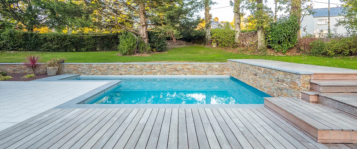 A pool deck with composite decking and retaining wall