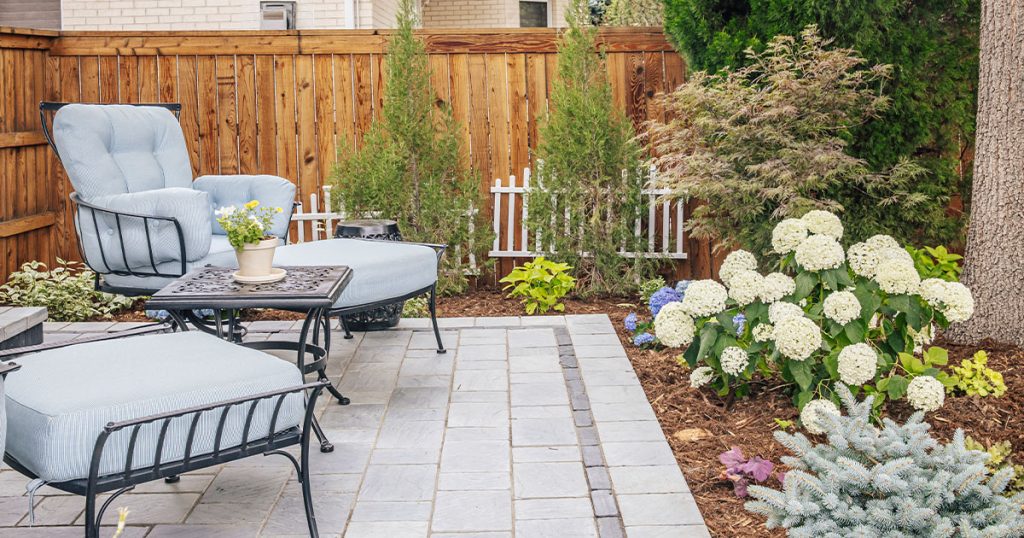 Patio designed by Land Designs By Colton with lush grenery and comfortable outdoor furniture