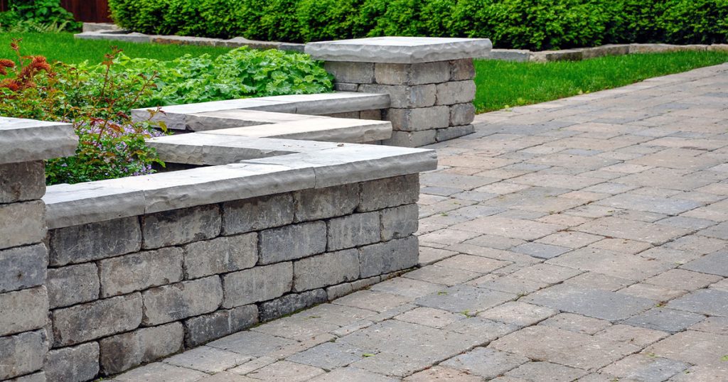 A brick patio with a retaining wall in an outdoor space