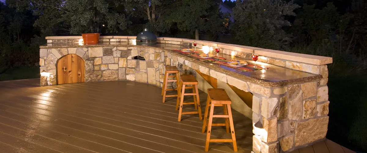 Elegant Centennial outdoor kitchen with stone bar, stools, and ambient lighting.
