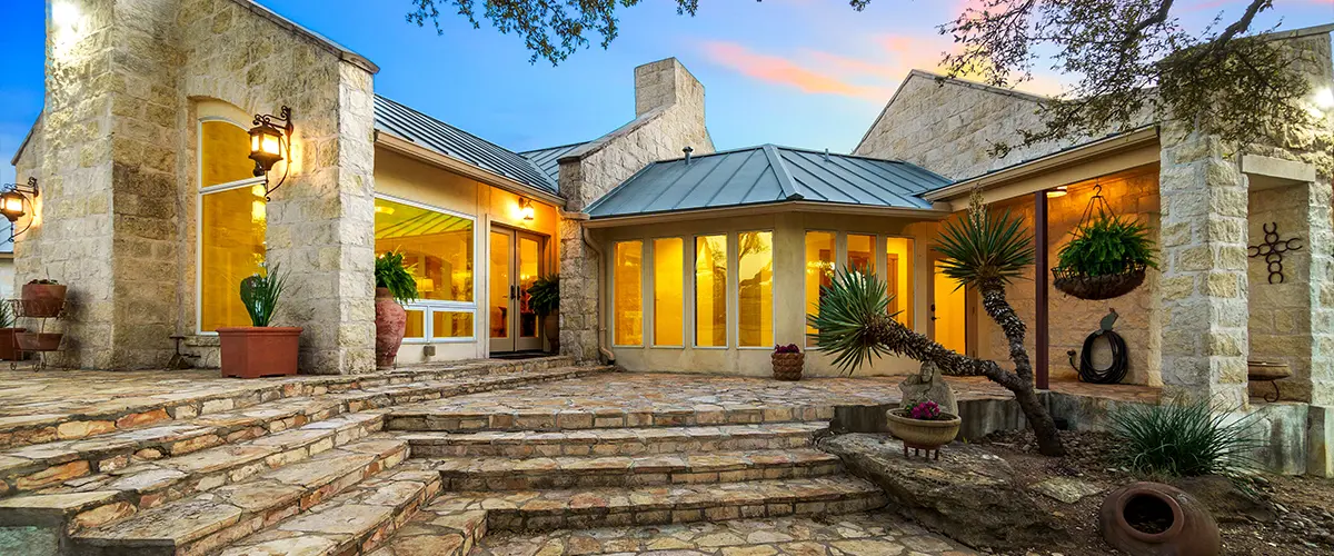 A luxury stone deck at sunset in front of house.