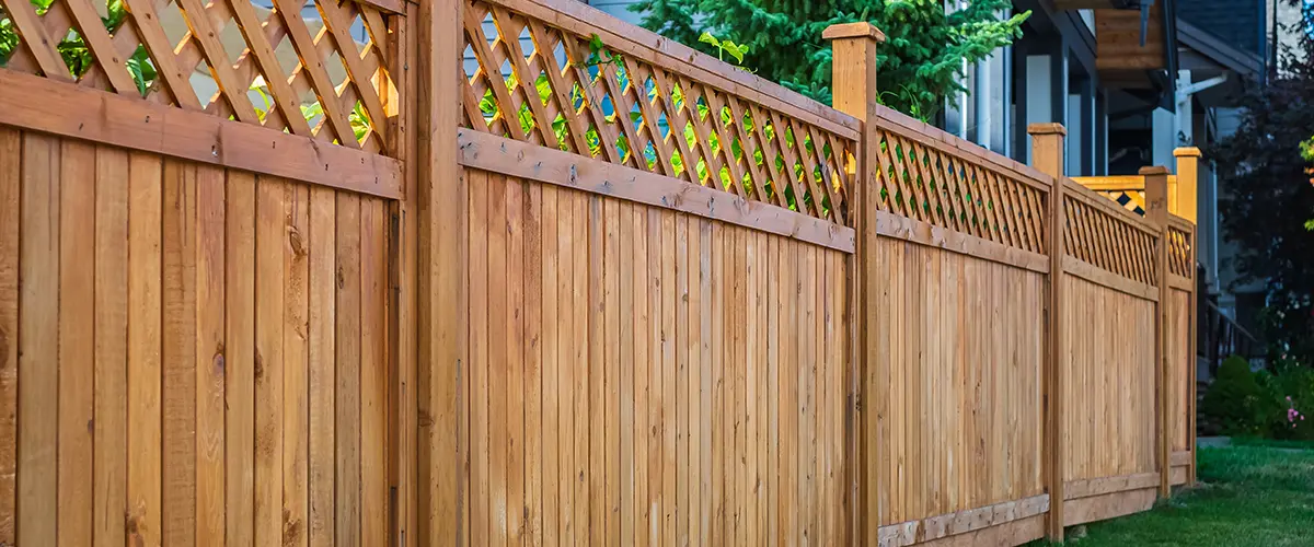 Sturdy wooden privacy fence installation in Arvada with decorative lattice top, enhancing backyard security.