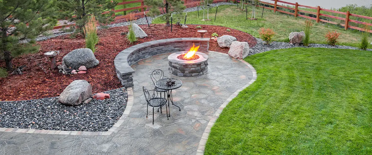 Scenic backyard with a fire pit, stone patio, and mountain view at sunset