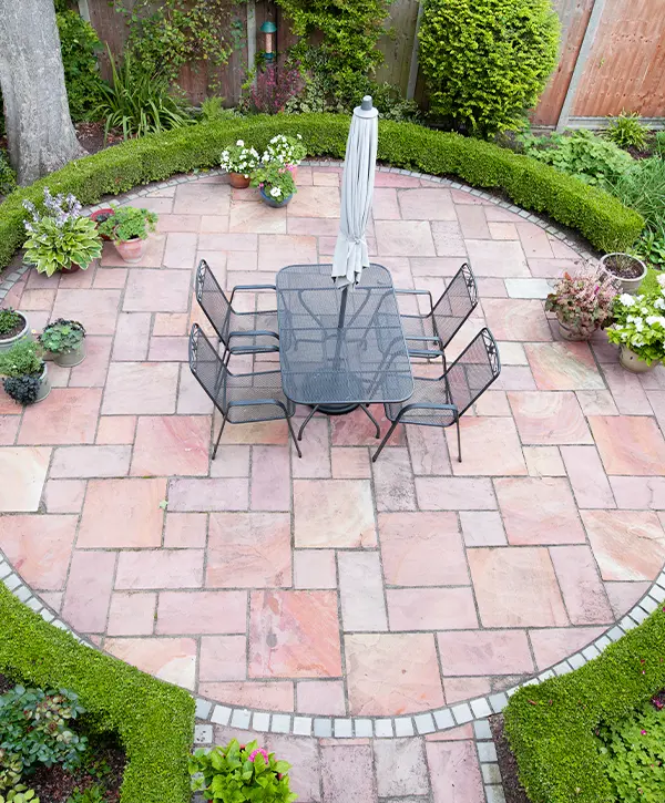 Aerial view of a circular garden patio with metal furniture and neatly trimmed hedges