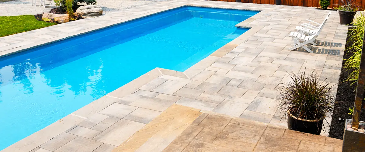 In-ground pool with paver deck and surrounding landscaping