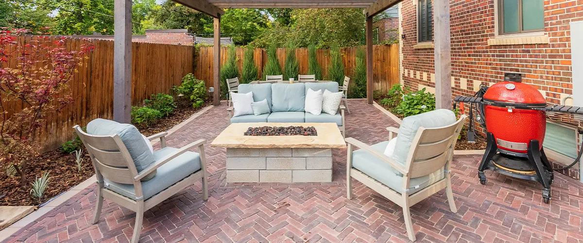 Backyard patio with wood pergola, fire pit, and outdoor seating on red brick pavers