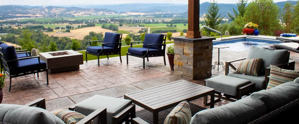 Luxury covered patio with stamped concrete flooring, outdoor furniture, and scenic valley view by pool