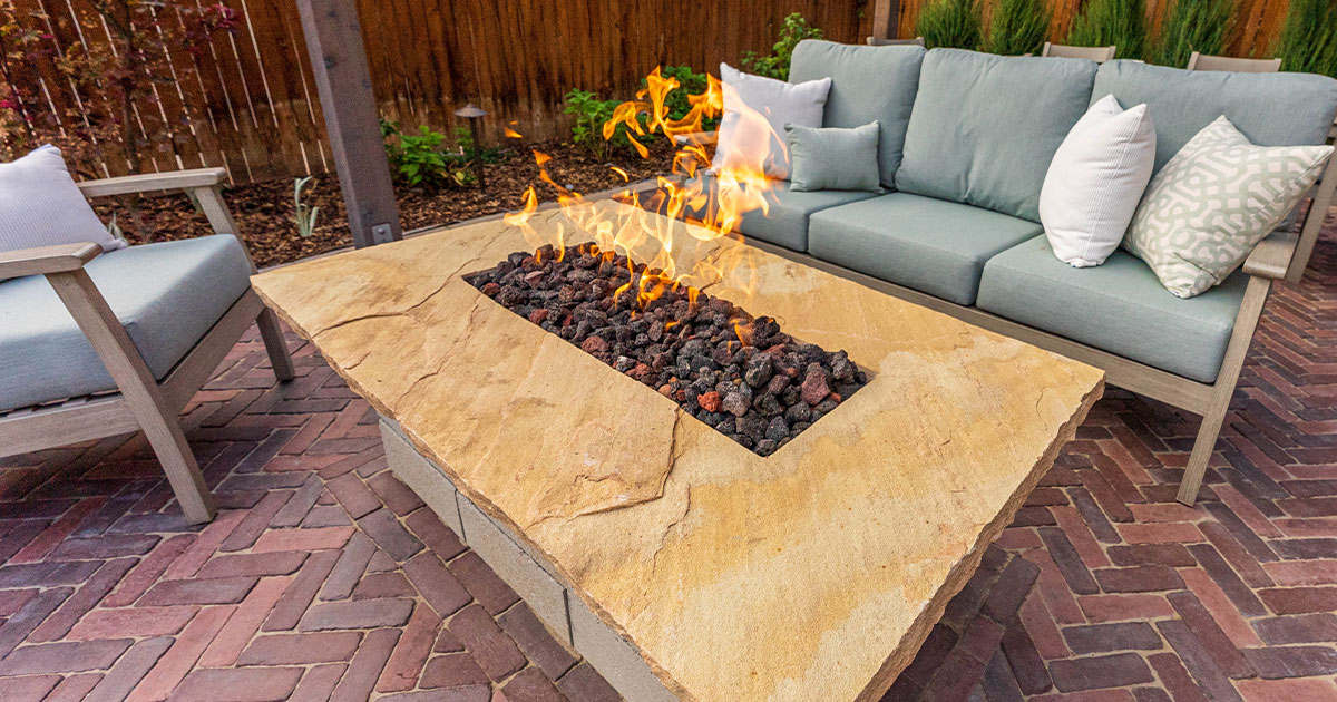 Modern backyard patio with fire pit, cushioned seating, and paver flooring for outdoor living space design