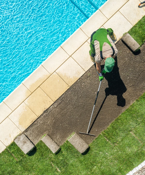 Worker doing pool landscaping near a swimming pool in Denver
