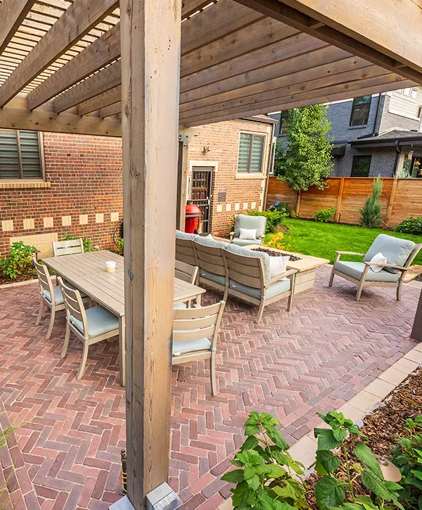 Paver patio with outdoor dining and seating under a wooden pergola featuring clean hardscape lines