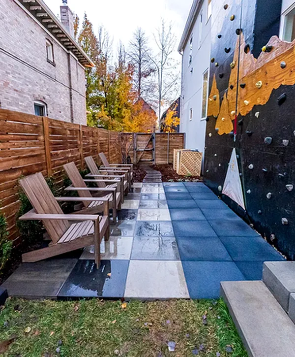 outdoor patio with wooden seating climbing wall professional hardscaping and privacy fence