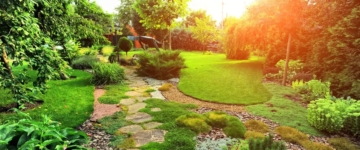 A serene garden featuring a stone path winding through lush green grass.
