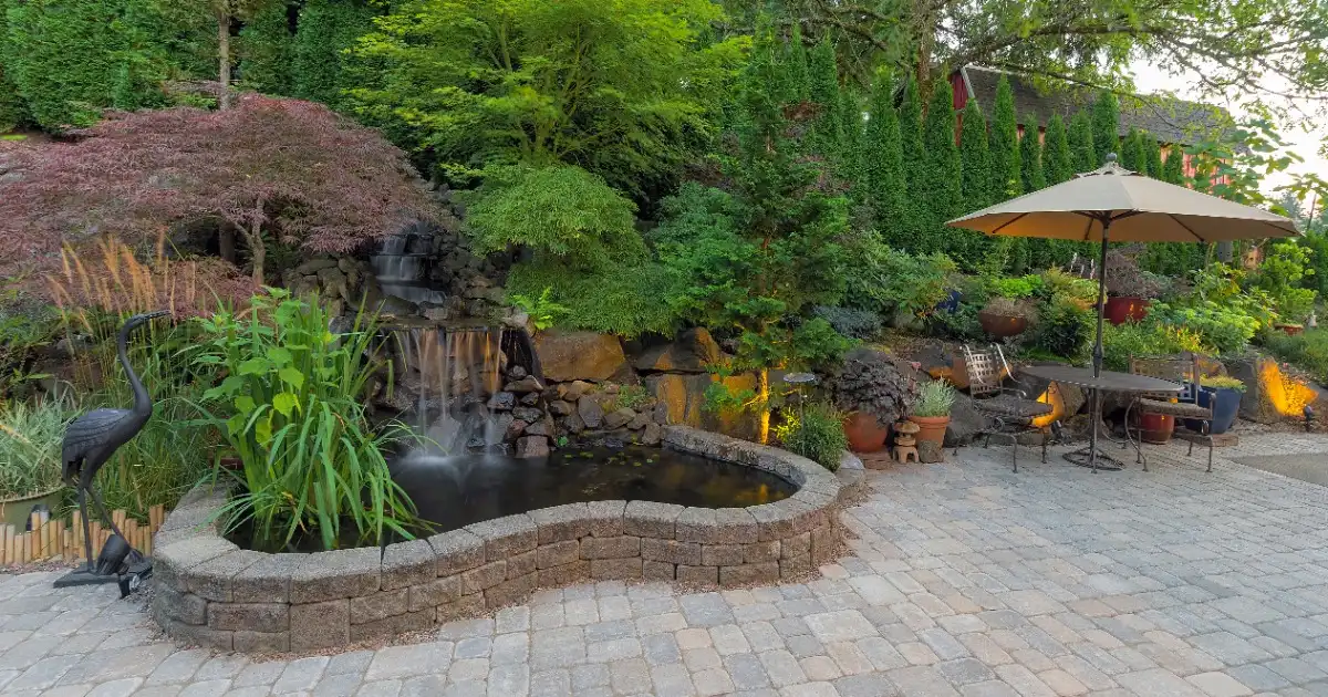 A serene patio featuring a cascading waterfall and a decorative fountain surrounded by lush greenery