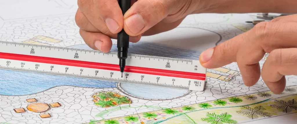 a person using an architect's scale ruler and a pen to draw a detailed landscape plan