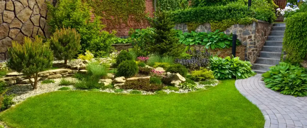 a beautifully landscaped garden featuring a variety of plants, a stone retaining wall, and a paved pathway