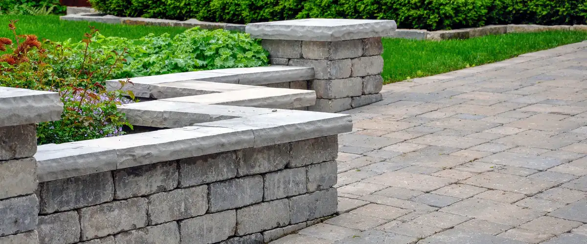 Detailed view of a grey stone retaining wall and matching paver walkway, showcasing high-quality residential hardscaping.