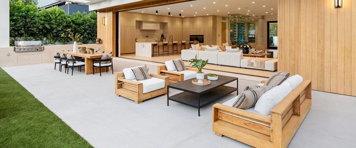 A high-quality cedar pergola providing shade for a cozy outdoor patio entertainment area with string lights.