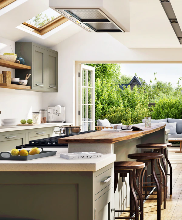 A bright, modern kitchen in Dakota Ridge, CO featuring sage green cabinetry and a live-edge wood breakfast bar that opens seamlessly via folding glass doors to an outdoor kitchen area.