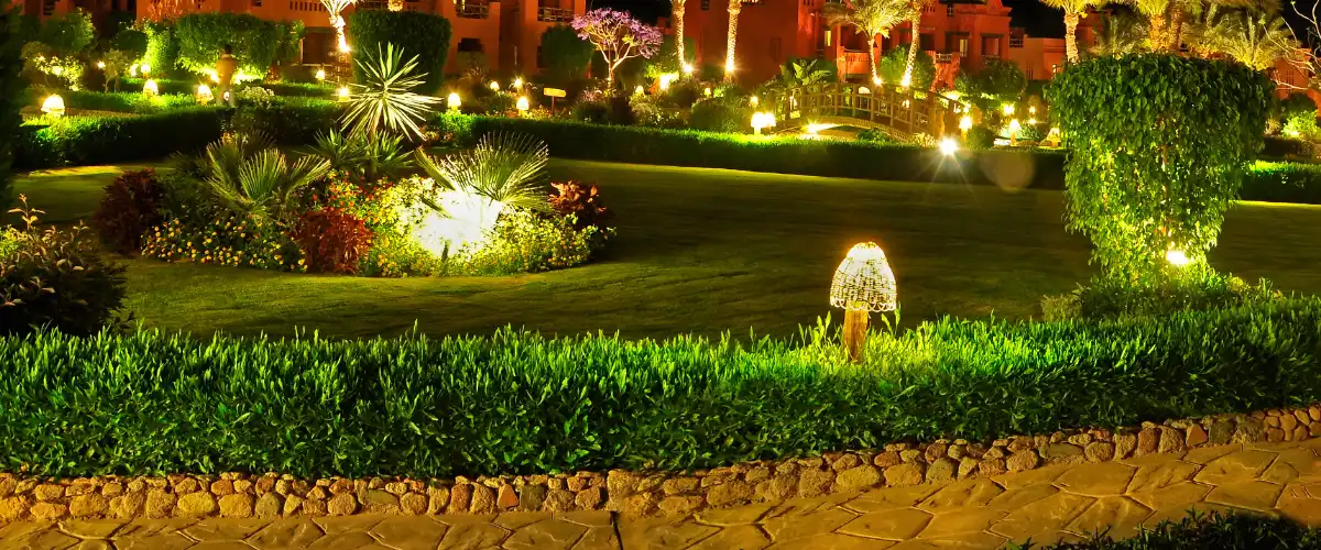 a beautifully landscaped garden illuminated with various landscape lighting fixtures